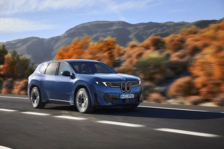 BMW iX3 Neue Klasse w ruchu na górskiej trasie - elegancki elektryczny SUV BMW w kolorze niebieskim, prezentowany przez dealera BMW M-Cars Małopolska.