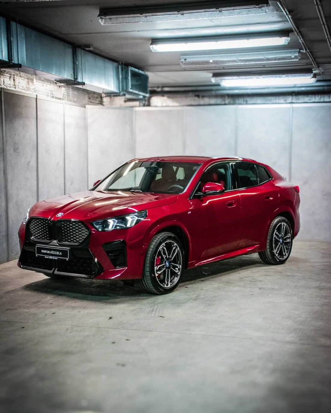 Czerwone BMW iX2 eDrive20 2025 w garażu, elektryczny SUV coupe dostępny w BMW M-Cars