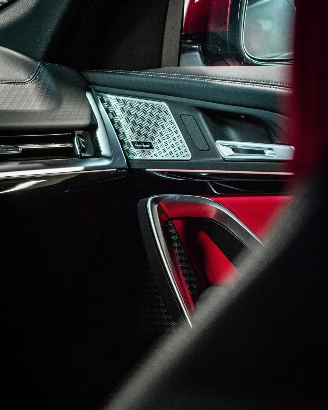 Detal wnętrza BMW iX2 eDrive20 2025, drzwi, głośnik Harman Kardon i czerwone wykończenie
