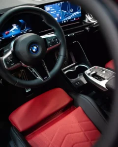 Kokpit BMW iX2 eDrive20 2025, czerwone sportowe fotele i zakrzywiony wyświetlacz BMW