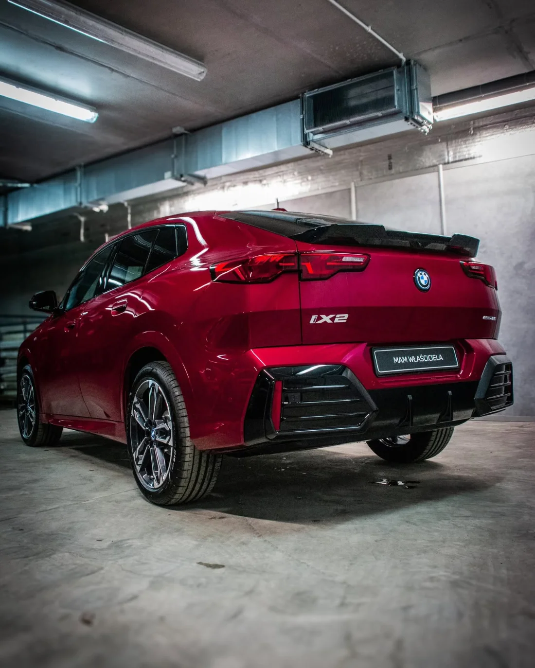 Tył czerwonego BMW iX2 eDrive20 2025, elektryczny SUV coupe BMW gotowy do odbioru