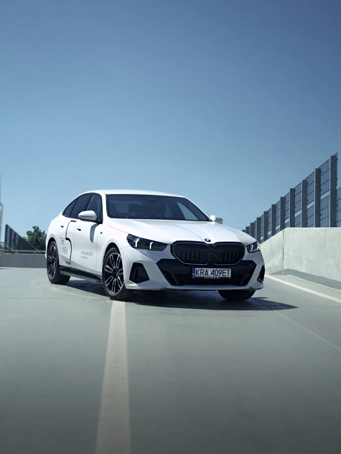 Białe BMW Serii 5 520d Limuzyna od przodu na parkingu, model dostępny w BMW M-Cars Kraków