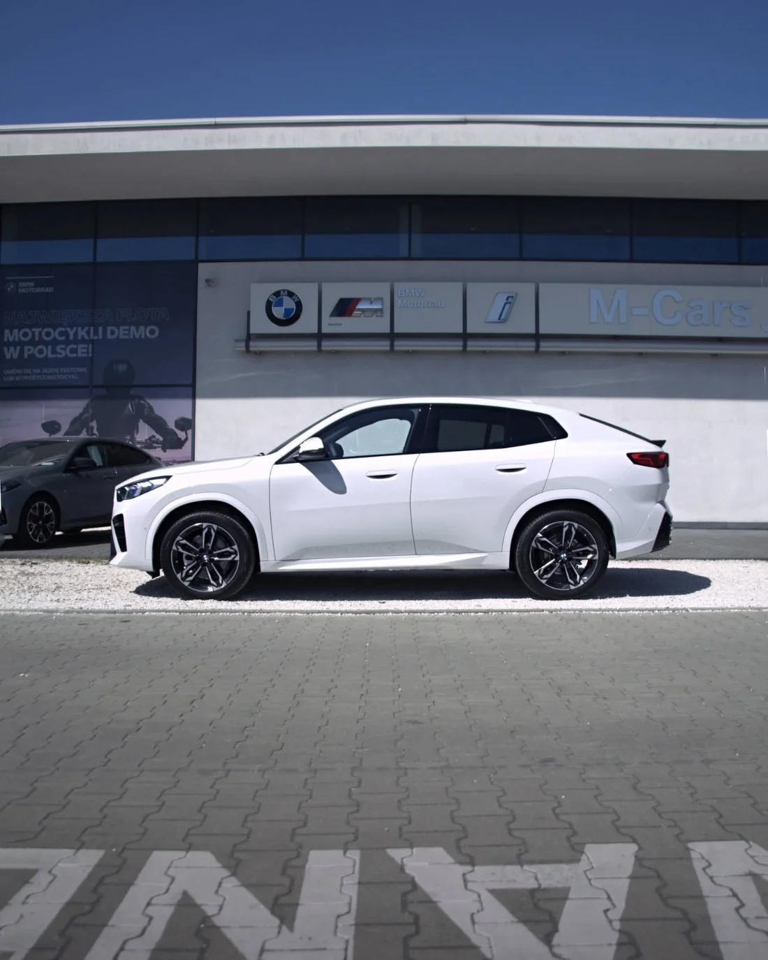 Białe BMW X2 20i z pakietem M z profilu przed salonem BMW M-Cars Kraków