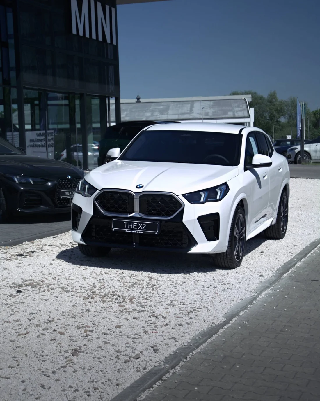 Białe BMW X2 20i z pakietem M, przód samochodu przed salonem M-Cars