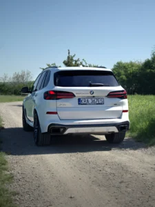 Tył BMW X5 xDrive30d 2025 na drodze szutrowej, biały SUV premium BMW M-Cars